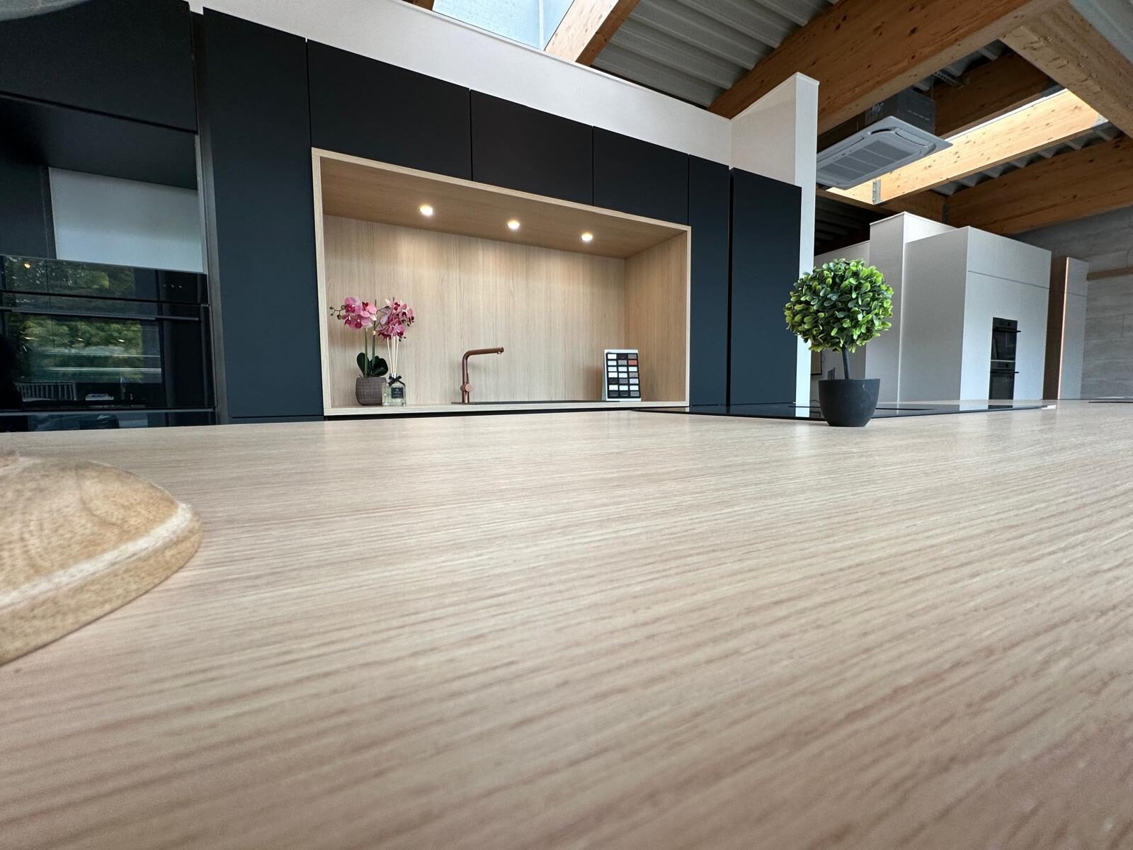 Cuisine en niche, façades noir mat, plan de travail et fond bois clair rétroéclairé